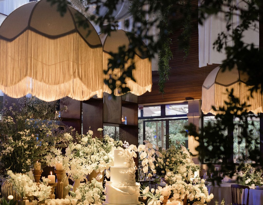Mesa de casamento com arranjo floral em tons vinho e branco ao entardecer